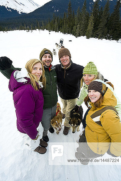 Group of tourists on a dog mushing tour pose for a picture in Moose Meadows at Alyeska Resort near Girdwood in Southcentral Alaska