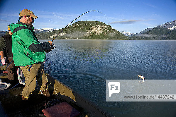 Ein Spinnfischer fängt einen Felchen  während er in einem Boot in den Big River Lakes in der Redoubt Bay State Critical Habitat Area in Süd-Zentral-Alaska steht  im Sommer