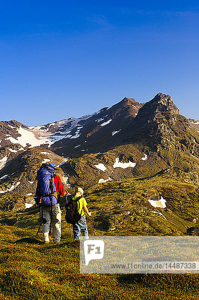 A father and son backpacking near Hatcher Pass in the Talkeetna Mountains with Bald Mountain Ridge in the background  Southcentral Alaska  Summer