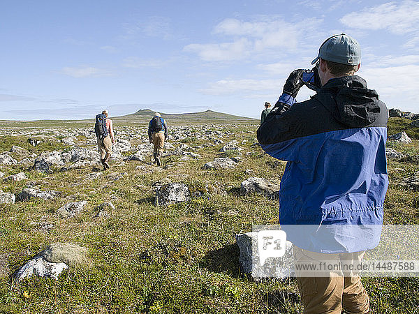 Man takes a picture of fellow hikers while trekking to volcanic peaks  St. Paul Island  Southwest Alaska  Summer