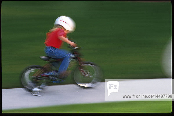 Kind auf dem Fahrrad auf dem Bürgersteig mit Helm SC AK Sommerporträt