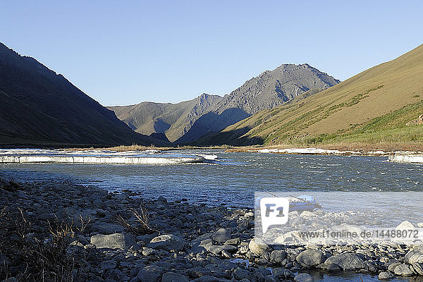 Scenic view of a raft beached along the riverbank of Kongakut River with residual ice melting ANWR Arctic Alaska Summer
