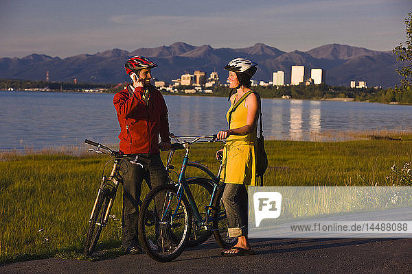 Radfahrer  die sich ausruhen und Selbstporträts entlang des Tony Knowles Coastal Trail mit der Skyline von Anchorage im Hintergrund machen  Southcentral Alaska