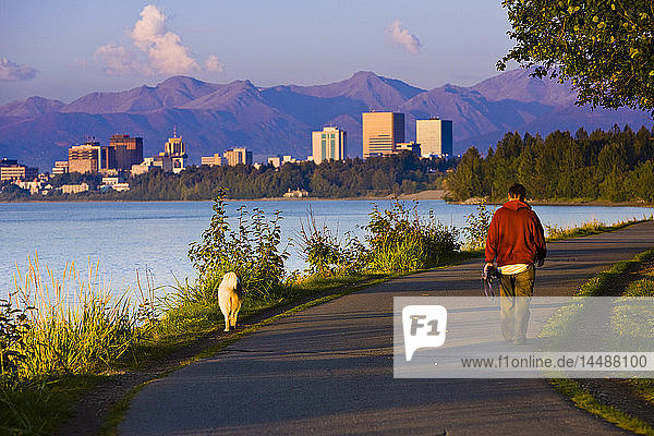 Jogger  Spaziergänger und Radfahrer auf dem Tony Knowles Coastal Trail mit der Skyline von Downtown Anchorage in der Ferne  Anchorage  Southcentral Alaska  Sommer