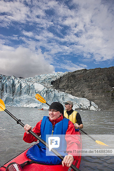Kayaking couple paddling with Shoup Glacier behind them  Shoup Bay State Marine Park  Southcentral Alaska