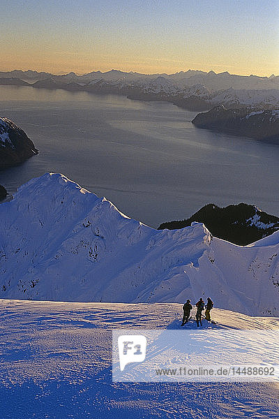 Luftaufnahme von 3 Extremskifahrern auf dem Bergrücken der Kenai Mtns bei Sonnenaufgang mit Resurrection Bay in der Ferne Alaska Winter