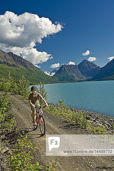 Ein Jugendlicher fährt mit seinem Mountainbike auf dem Eklutna Lake Radweg im Sommer in Süd-Zentral-Alaska