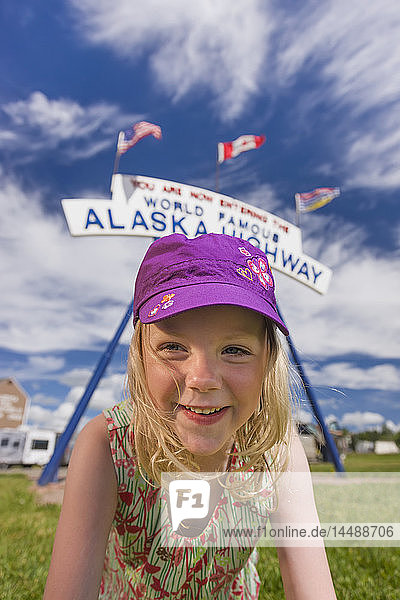 Ein junges Mädchen unter dem weltberühmten Alaska Highway Schild  Dawson Creek  British Columbia  Kanada  Sommer