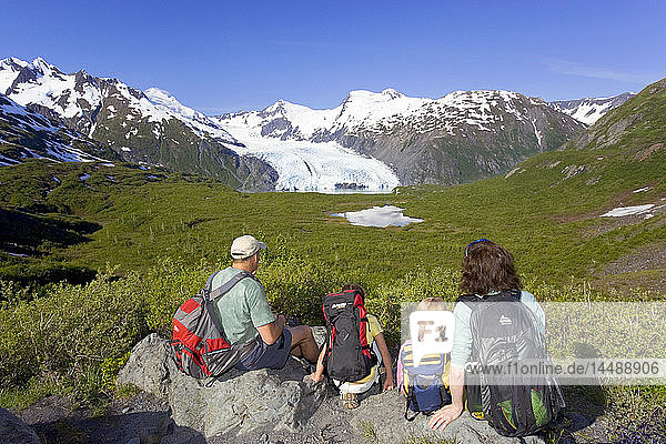 Family sitting on rock viewing Portage Glacier from Portage Pass Trail Chugach Mtns Alaska Summer