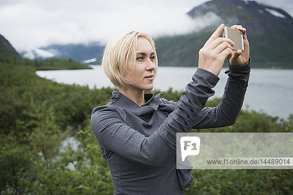 Frau benutzt ein Smartphone zum Fotografieren im Portage Valley  Southcentral Alaska