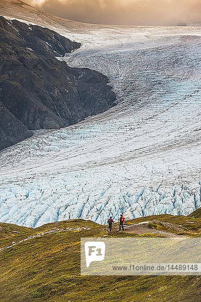 Ein Mann und eine Frau wandern auf dem Harding Icefield Trail mit dem Exit Glacier im Hintergrund  Kenai Fjords National Park  Kenai Penninsula  Southcentral Alaska