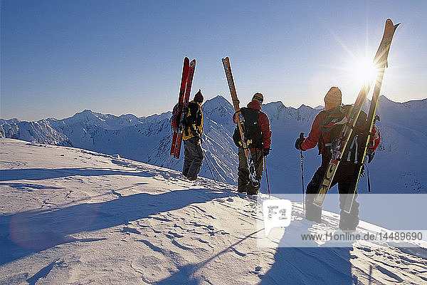 3 Extremskifahrer stehen auf einem Bergrücken mit Blick auf den Turnagain Arm Chugach Mtns in der Sonne Southcentral Alaska Winter