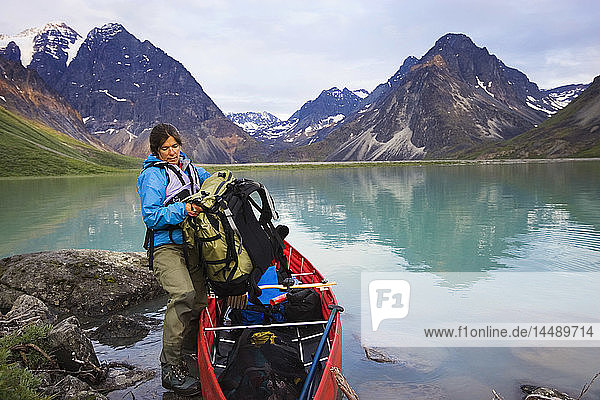Woman loading gear into portable canoe Turquoise Lake at Lake Clark National Park SC AK Summer