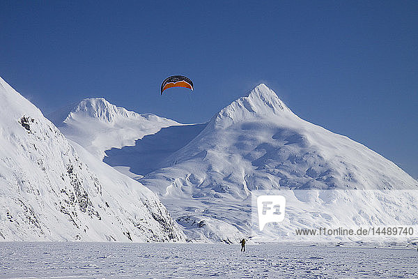 Ein Kite-Skifahrer fährt auf dem Portage-See mit den Chugach Mountains im Hintergrund  Southcentral  Alaska