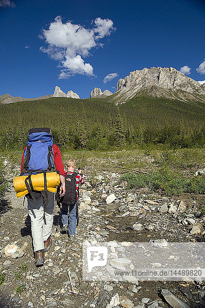 Man and child hiking along a small unnamed stream in the Brooks Range during Summer in Arctic Alaska