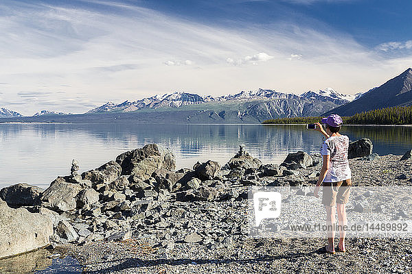 Eine Frau fotografiert den Kluane Lake mit einem Smartphone  Yukon Territory  Kanada  Sommer.