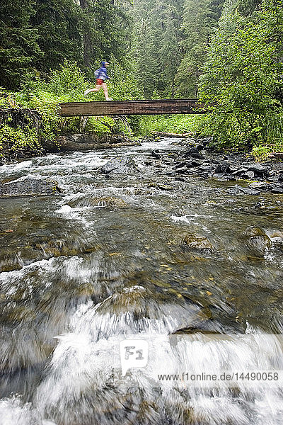 Läuferin beim Überqueren einer Brücke auf dem Resurrection River Trail Chugach National Forest Kenai Peninsula Alaska Sommer