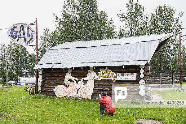 Touristin fotografiert eine Blockhütte in der Tetsa River Lodge  British Columbia  Kanada  Sommer