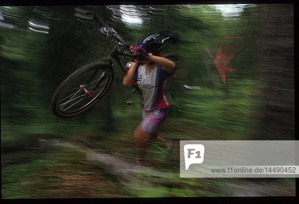 Mtn Biker trägt Fahrrad über Baum in Radrennen Alaska Sommer Porträt