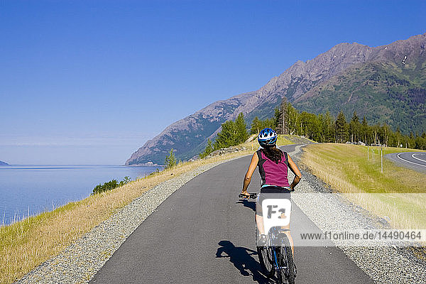 Radfahrer auf dem Coastal Trail mit Blick auf den Turnagain Arm und die Kenai Mountains in der Nähe von Bird Creek in Süd-Zentral-Alaska
