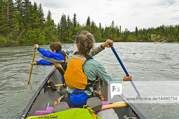 Family canoeing on Eagle River in Chugach State Park during Summer in Southcentral Alaska