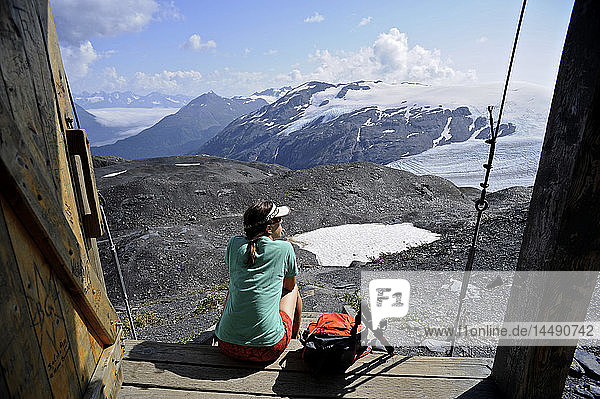 Female backpacker rests and enjoy the view from an alpine hut along the Harding Icefield trail  Kenai Fjords National Park  Kenai Peninsula  Southcentral Alaska  Summer