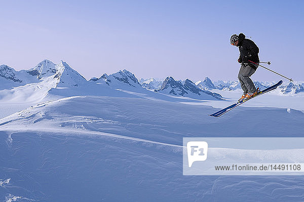 Alpiner Skifahrer beim Sprung mit dem Juneau-Eisfeld und dem Rhino Peak im Hintergrund im Südosten Alaskas. Komposit