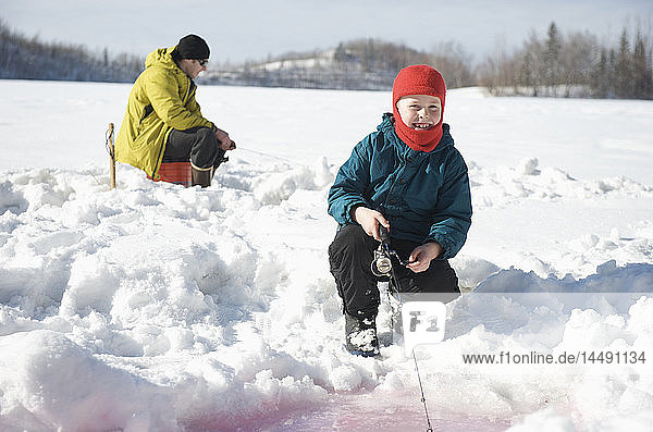Boy ice fishing on Matanuska Lake in the Matanuska Valley north of Anchorage  Southcentral Alaska