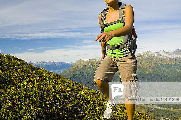 Junge erwachsene hispanische Frau beim Wandern auf dem Gipfel des Berges Alyeska mit Blick auf die Chugach Mountains in der Nähe von Girdwood in Süd-Zentral-Alaska