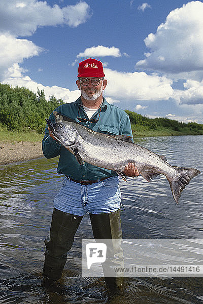 Fischer mit großem Königslachs am Ufer des Nushagak River im Südwesten von AK Sommer