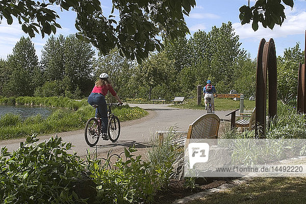 Young Man & Woman Bike on Anchorage Coastal Trail AK SC Summer
