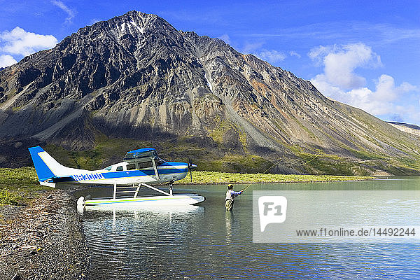 Woman flyfishing on Turquoise Lake near Cessna floatplane Lake Clark Nat Park Southcentral AK Summer