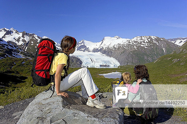 Family sitting on rock viewing Portage Glacier from Portage Pass Trail Chugach Mtns Alaska Summer