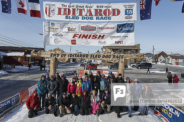 A portion of the mushers who finished the 2015 Iditarod as of 2pm on Saturday March 21st pose at the finish line in Nome for a group photo
