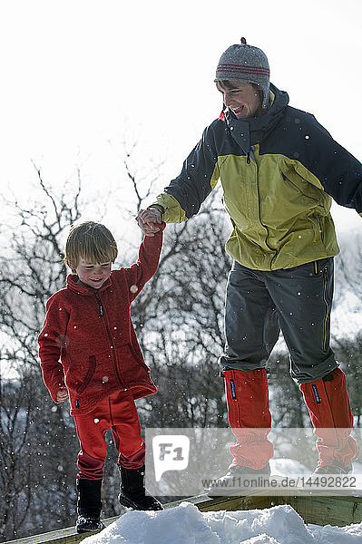 Mutter und Sohn stehen auf einem Geländer im Schnee
