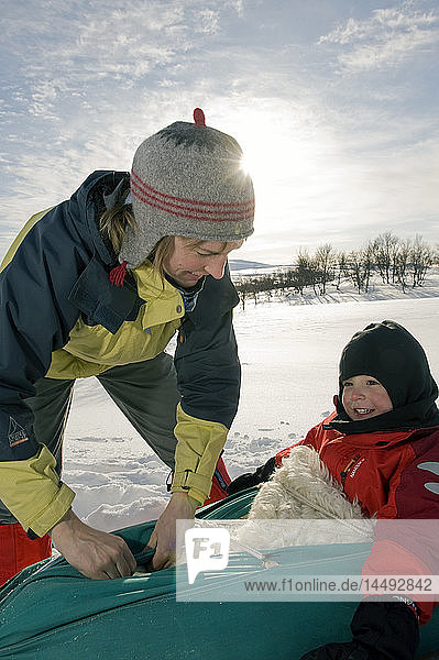 Mother and son tobogganing outdoors in snow