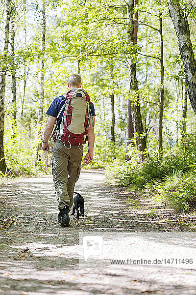 Man with dog walking through forest