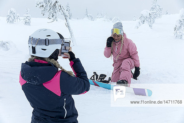 Frauen fotografieren beim Snowboarden