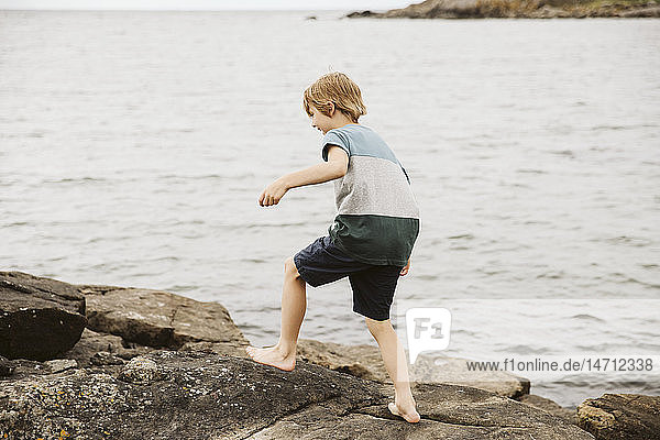 Junge läuft am Meer auf Felsen