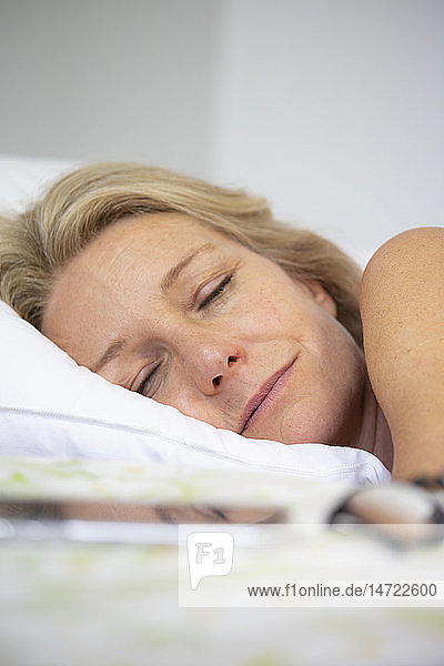 Eine Frau schläft neben ihrem Smartphone.