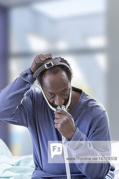 Mann mit einer CPAP-Maske (Continuous Positive Airway Pressure) zur Behandlung des Schlafapnoe-Syndroms.