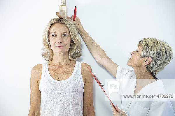 Woman measuring herself with a height measuring rod.