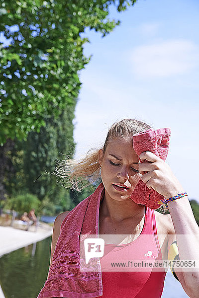 Frau wischt sich nach dem Sport das Gesicht ab.