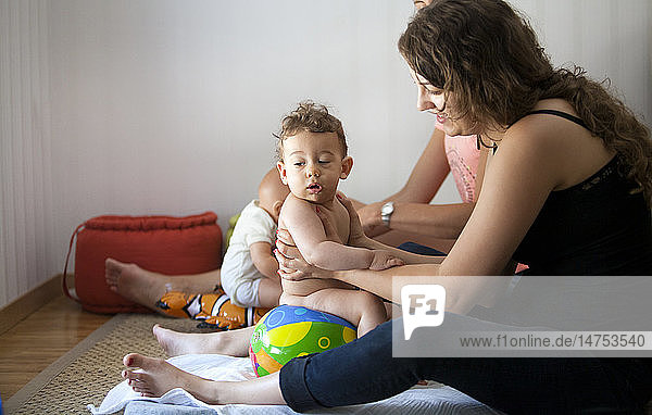 Reportage on a baby massage lesson with a certified masseur. A young mother learns how to massage her 1-year old son.