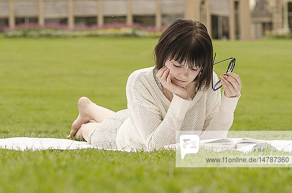 Junge Frau liest ein Buch in einem Park.