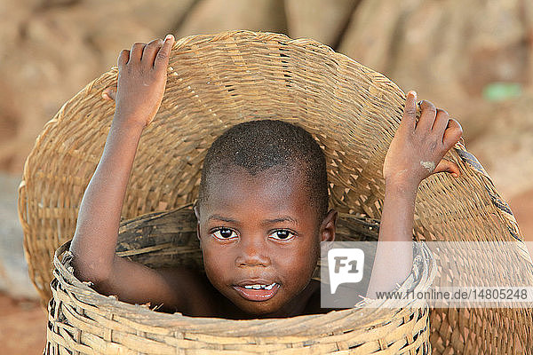 Porträt. Afrikanisches Kind versteckt sich in einem Weidenkorb.