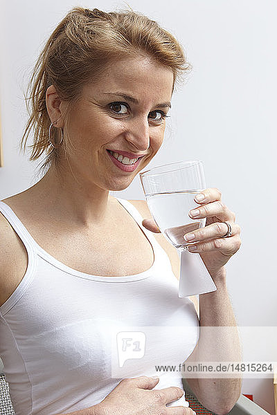 Schwangere Frau trinkt Wasser.