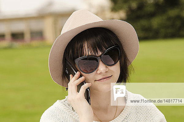 Junge Frau telefoniert in einem Park.