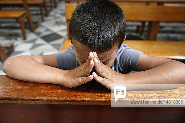 8-year-old boy praying in church.