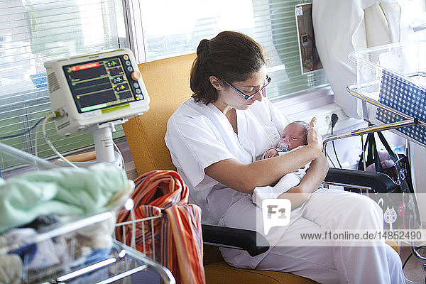 Reportage aus der Neonatologie der Stufe 2 in einem Krankenhaus in Haute-Savoie  Frankreich. Ein Frühgeborenes wird bis zum Erreichen seiner vollen Größe überwacht. Eine Krankenschwester tröstet es.